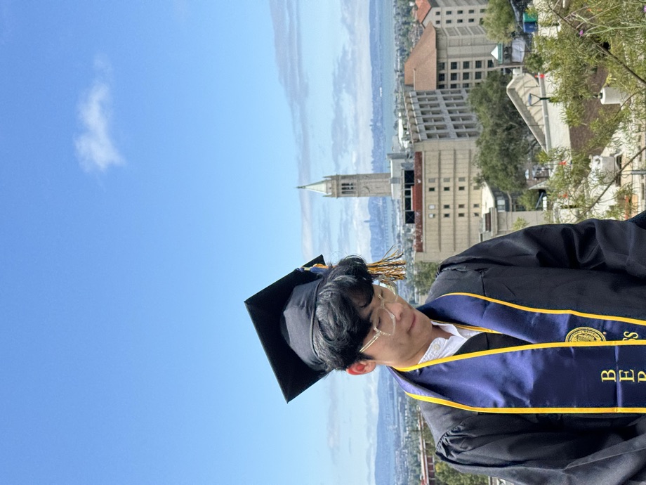 In cap and gown at UC Berkeley with the Campanile behind